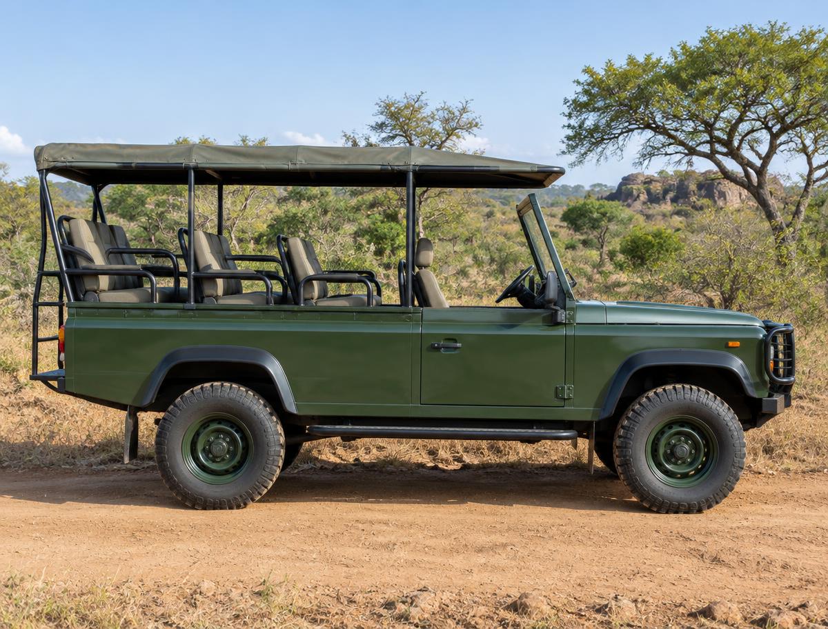 Side view of a green open safari jeep on a dirt road